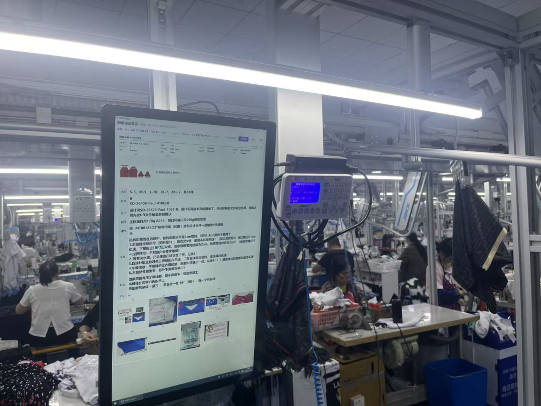 Sewing workstation with on-screen production specifications and overhead garment racks